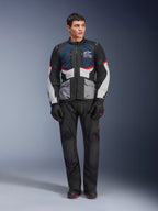 Alpinestars Andes Air Drystar® Jas, motortouringjas, Deep Blue Black en Ice Gray, gedragen met bijpassende zwarte adventure-broek en handschoenen, voorzien van mesh-panelen voor luchtstroom en een technisch ontwerp met meerdere zakken.