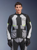 Mannelijke motorrijder in Alpinestars Andes Air Drystar® jas in Ice Gray, Dark Gray en zwart, voorzien van neongele accenten en mesh ventilatiepanelen, gecombineerd met bijpassende motorbroek en handschoenen, adventure touring uitrusting
