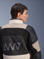 Alpinestars AMT-10LAB Drystar® XF jas, achteraanzicht op mannelijk model, kleurstelling White Sand Aluminum Camo en zwart, met grote AMT-branding, mesh ventilatiepanelen en lederen verstevigingen, technische adventure motorkleding