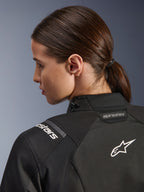 Alpinestars Stella Andes V4 Drystar® damesjas, zwart, detailopname van de bovenrug en schouder, voorzien van wit geborduurd Astar-logo en merknaam, technische textielconstructie voor adventure motorrijden