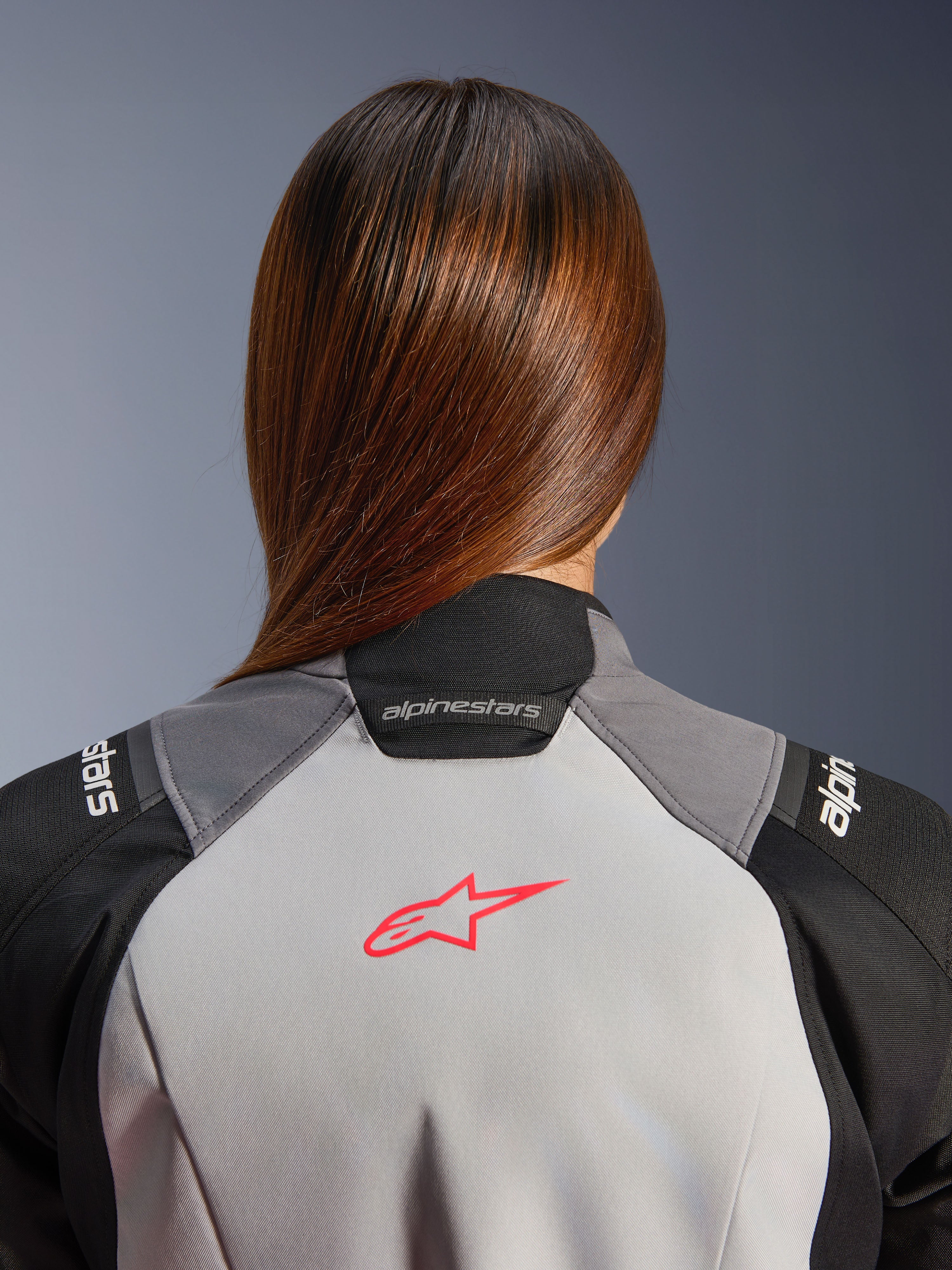 Alpinestars Stella Andes V4 Drystar damesjas, grijze en zwarte adventure motorjas met koraalrood logo op de rug.