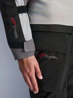 Close-up detail van de mouw van de Alpinestars Stella Andes V4 Drystar® damesjas en bijpassende broek, met het Drystar-logo, ijsgrijze en zwarte textielconstructie, waterdichte branding voor adventure touring-uitrusting