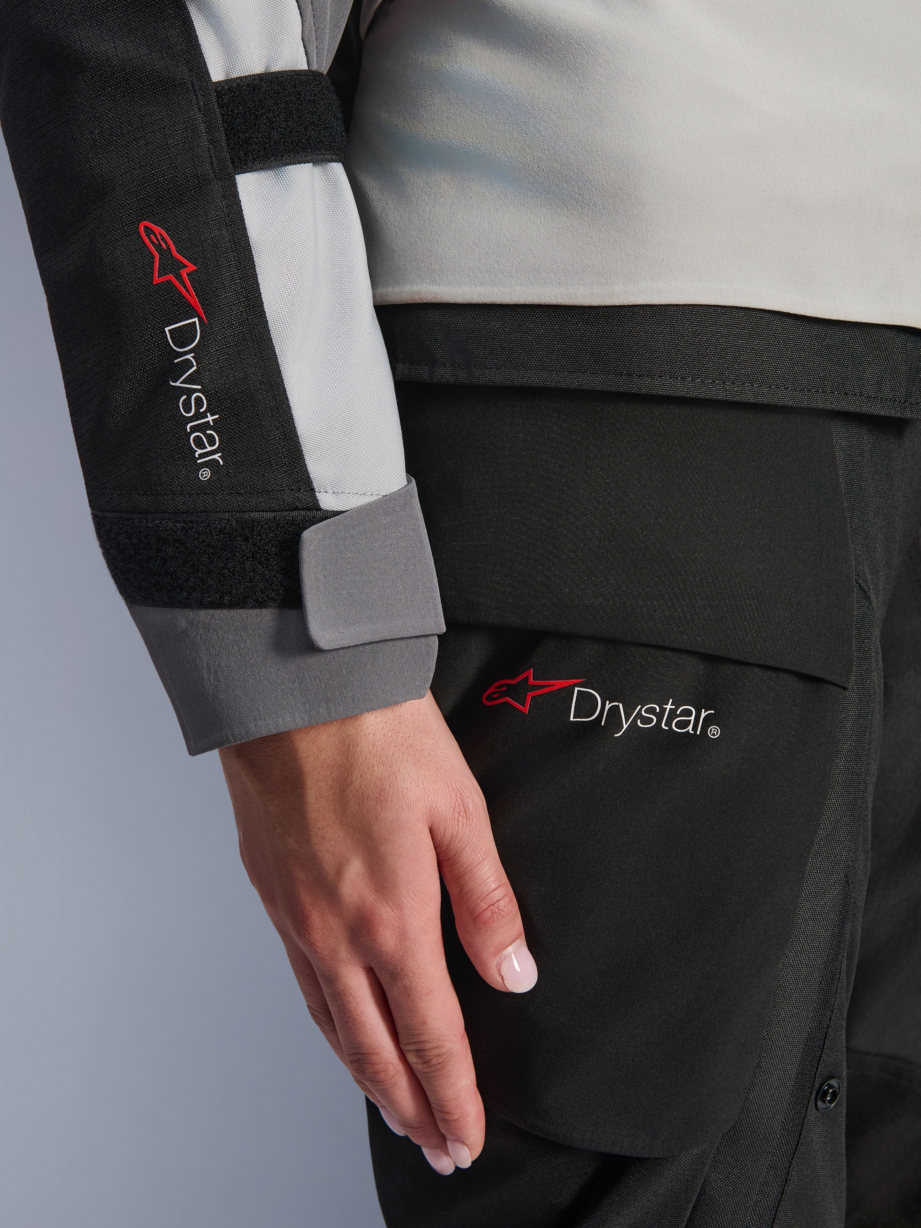Close-up detail van de mouw van de Alpinestars Stella Andes V4 Drystar® damesjas en bijpassende broek, met het Drystar-logo, ijsgrijze en zwarte textielconstructie, waterdichte branding voor adventure touring-uitrusting