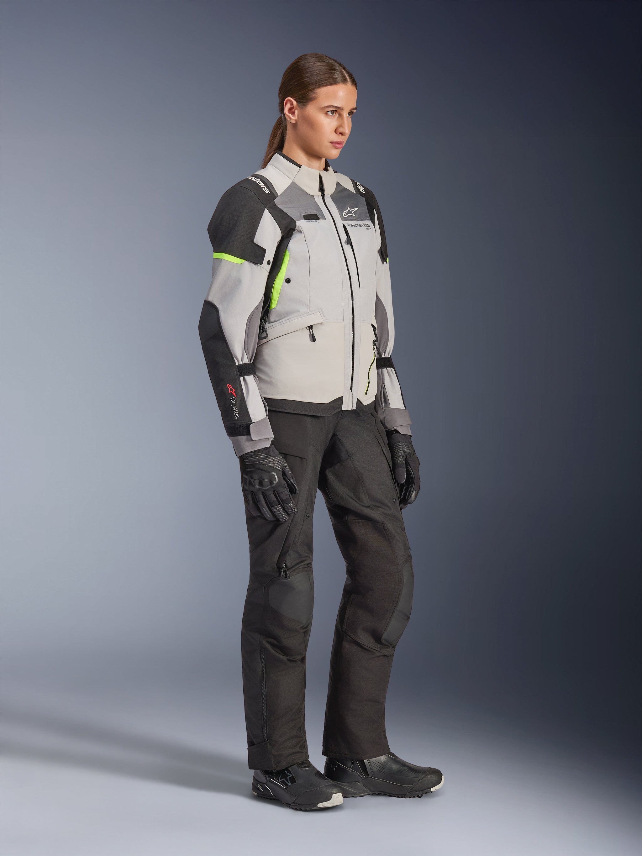 Alpinestars Woman Stella Andes V4 Drystar® Jacket, Ice Gray Dark Gray and Black with Yellow Fluo accents, worn by a female model with black motorcycle pants and gloves, adventure touring protective gear for women