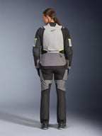 Vrouwelijke rijder van achteren die de Alpinestars Stella Andes V4 Drystar® jas en bijpassende broek draagt, Ice Gray en Dark Gray met zwarte en fluogeel accenten, adventure-touring motorkleding met duurzame textielconstructie en reflecterende branding
