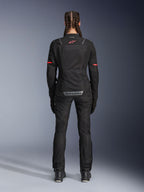Alpinestars Stella ST-2 Air jas, dames motorjas, zwart, achteraanzicht met rood logo op de bovenrug en grijze branding op de onderrug, gedragen met bijpassende zwarte motorbroek en laarzen, modern touring-ontwerp met mesh-panelen en reflecterende details