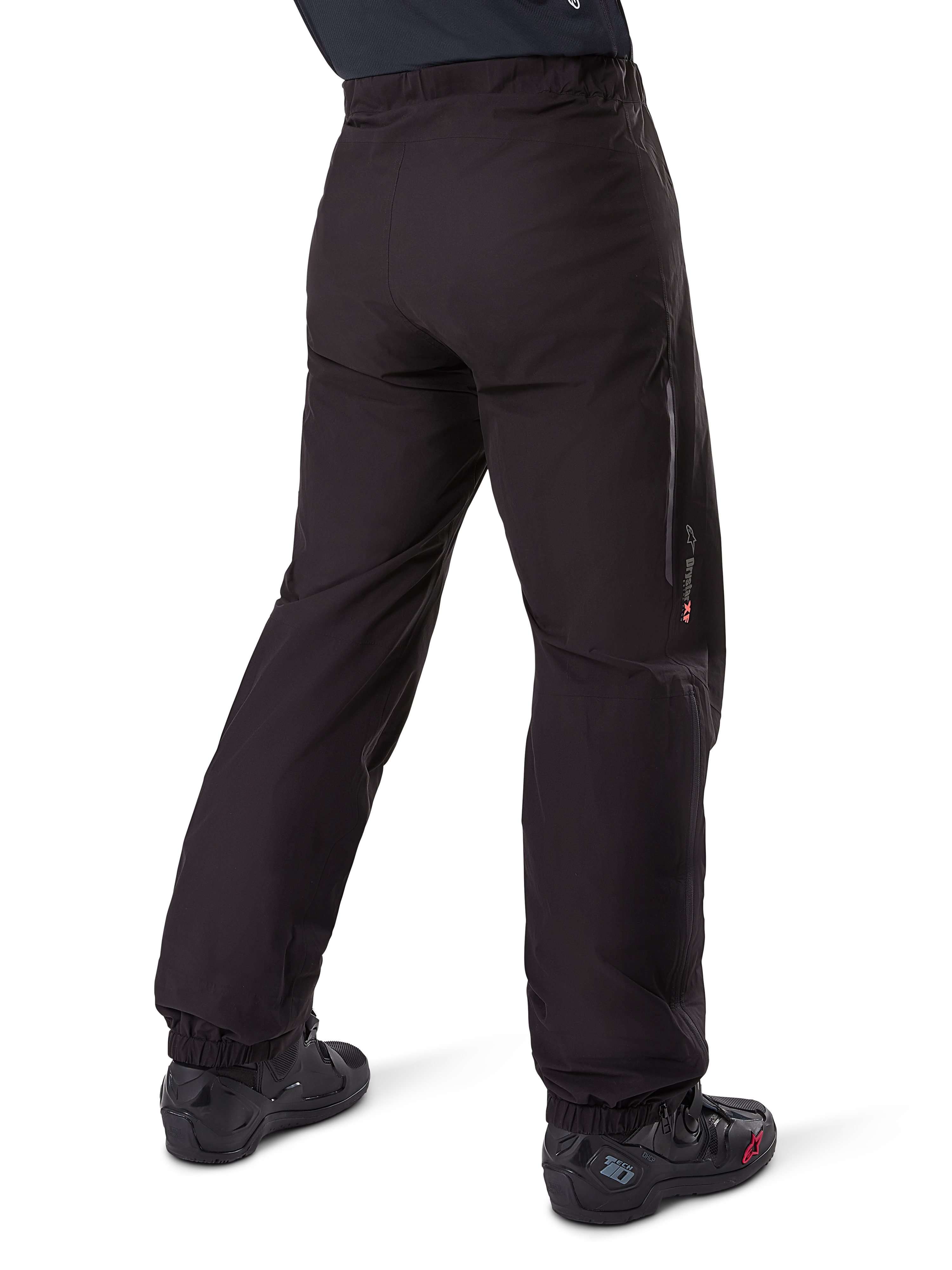 Alpinestars Amt-8 Stretch Drystar® XF broekvoering, zwart, achteraanzicht van de waterdichte voering gedragen over zwarte motorlaarzen, voorzien van Drystar XF-branding op het onderbeen, elastische enkelboorden en lichtgewicht stretchmateriaal voor adventure-touring.
