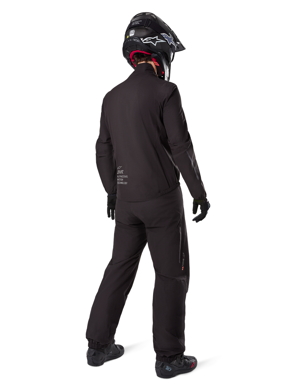 Motorrijder van achteren gezien, gekleed in de zwarte Amt-8 Stretch Drystar® XF Broek en bijbehorende jas, volledige adventure touring outfit met zwarte helm en laarzen, technische waterdichte en rekbare uitrusting voor lange motorritten