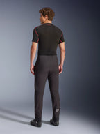 Alpinestars Aeroshell Pants, Black, softshell motorcycle pants, back view on a model, featuring a modern tapered fit, white Astars logo on the lower leg, and elasticated hems, worn with a black short-sleeved base layer and riding shoes.