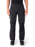 Alpinestars Hyde XT Drystar broek, zwarte adventure touring motorbroek, gedragen door een rijder met zwarte laarzen, voorzien van grijze logo's op de dijen, geïntegreerde riem, versterkte kniepanelen en waterdichte textielconstructie