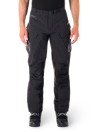 Alpinestars Hyde XT Drystar broek, zwarte adventure touring motorbroek, gedragen door een rijder met zwarte laarzen, voorzien van grijze logo's op de dijen, geïntegreerde riem, versterkte kniepanelen en waterdichte textielconstructie
