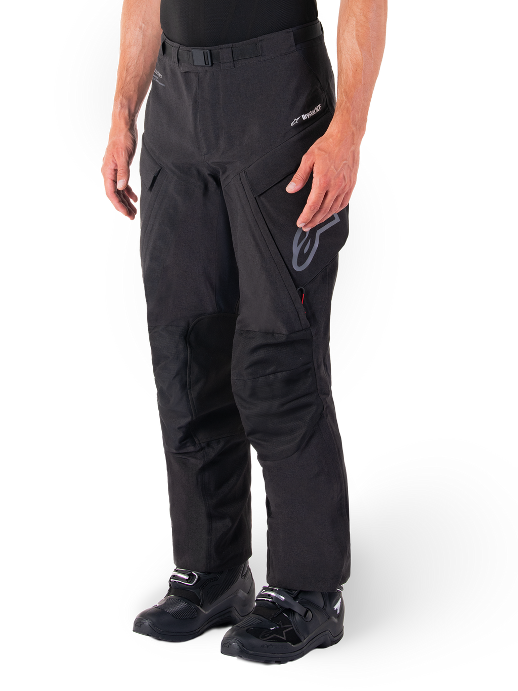 Alpinestars Hyde XT Drystar® broek, adventure touring motorbroek, zwart, gedragen met zwarte laarzen, voorzien van gelamineerde Drystar®XF membraan-branding, versterkte kniepanelen en cargozakken met ritssluiting.