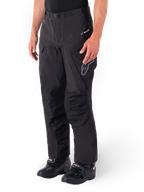 Alpinestars Hyde XT Drystar® broek, adventure touring motorbroek, zwart, gedragen met zwarte laarzen, voorzien van gelamineerde Drystar®XF membraan-branding, versterkte kniepanelen en cargozakken met ritssluiting.