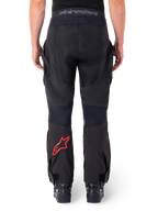 Alpinestars Hyde XT Drystar® broek, adventure motorbroek, zwart met rood sterlogo op het onderbeen, achteraanzicht, over-de-laars enduro-ontwerp met duurzame textielpanelen en tailleband met merklogo.