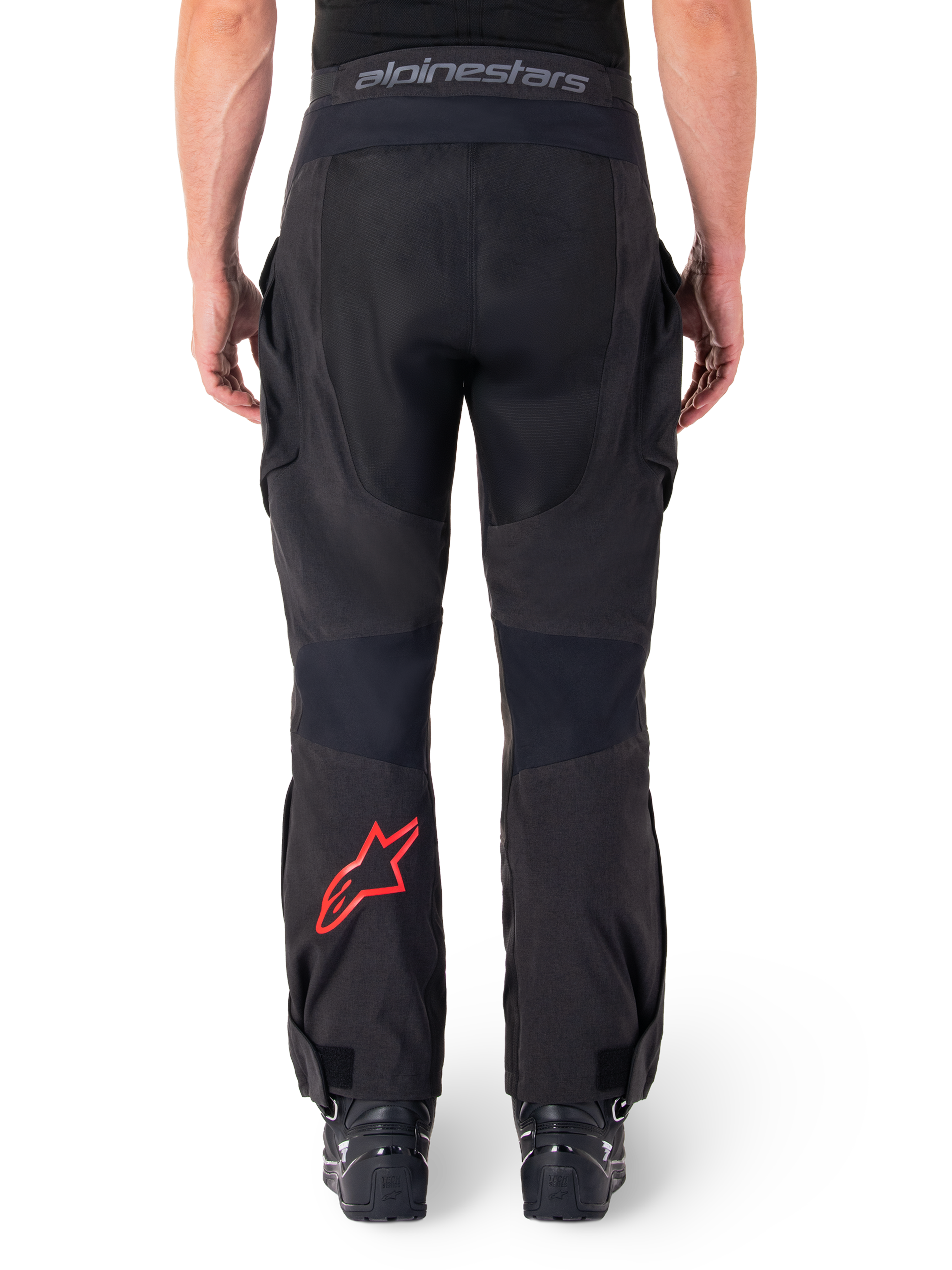 Alpinestars Hyde XT Drystar® broek, adventure motorbroek, zwart met rood sterlogo op het onderbeen, achteraanzicht, over-de-laars enduro-ontwerp met duurzame textielpanelen en tailleband met merklogo.