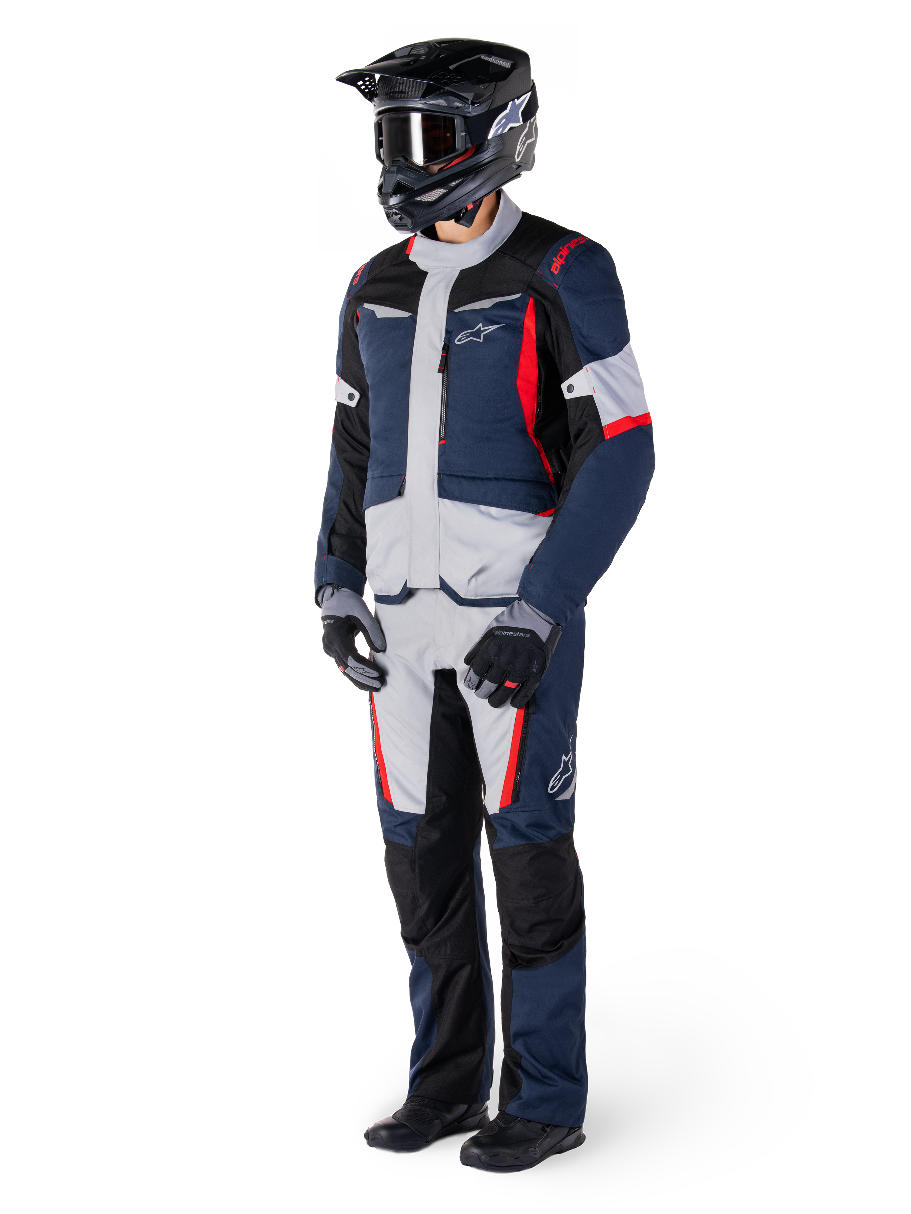 Alpinestars St-1 Waterproof broek, adventure touring broek, donkerblauw, zwart en felrood, gedragen met een bijpassend touringjack, zwarte helm, handschoenen en laarzen, voorzien van lichtgrijze panelen, rode accenten en Alpinestars-branding, ontworpen voor rijden in alle weersomstandigheden.