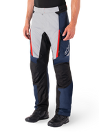 Alpinestars St-1 Waterproof Broek, motor tourbroek, donkerblauw, zwart en helderrood, voorzien van lichtgrijze voorpanelen met rode ritsaccenten, zwarte verstevigde kniestukken en een wit Alpinestars-logo op de zijkant, gedragen met zwarte motorlaarzen.