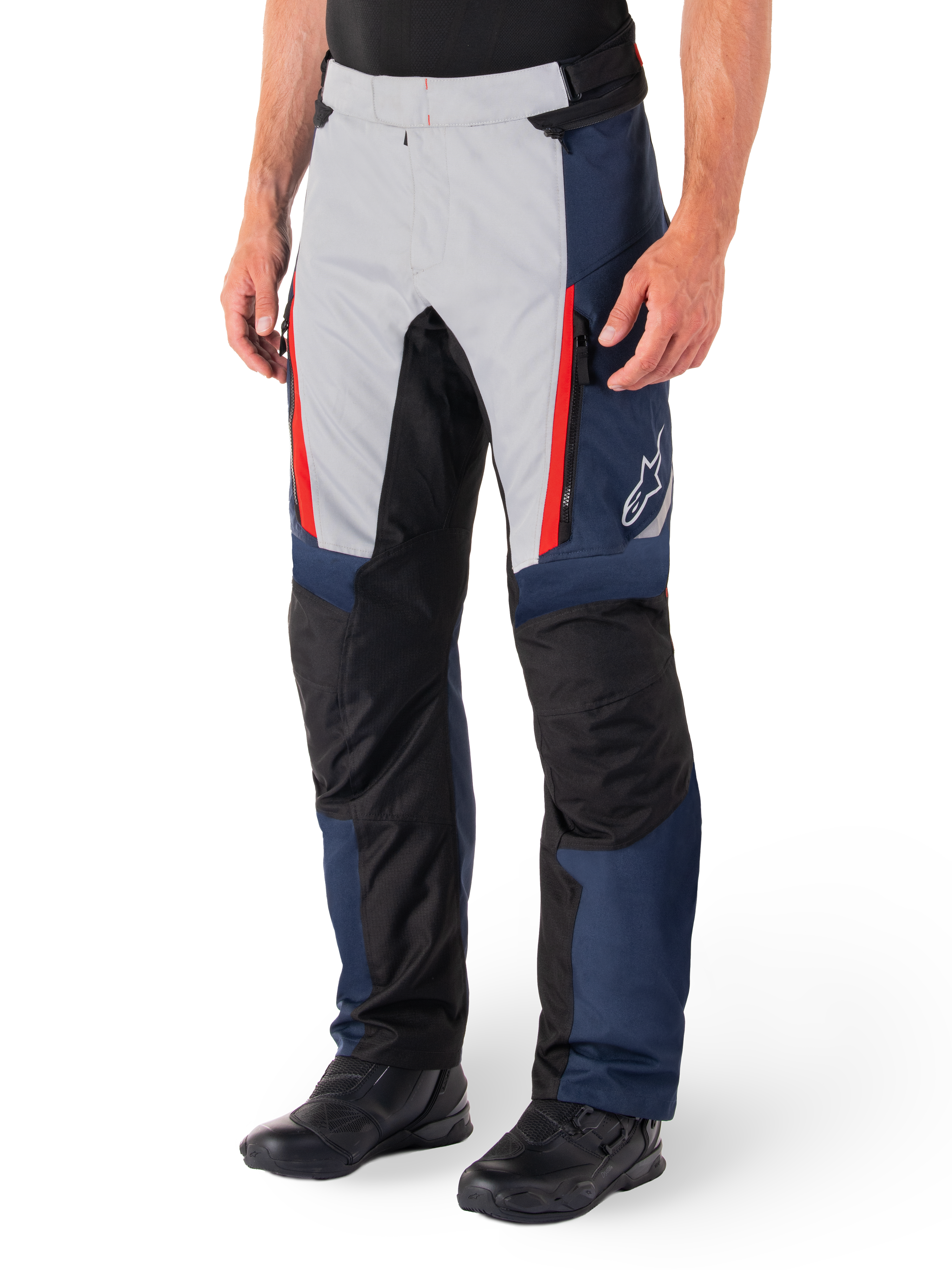Alpinestars St-1 Waterproof Broek, motor tourbroek, donkerblauw, zwart en helderrood, voorzien van lichtgrijze voorpanelen met rode ritsaccenten, zwarte verstevigde kniestukken en een wit Alpinestars-logo op de zijkant, gedragen met zwarte motorlaarzen.
