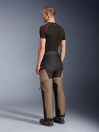 Alpinestars Andes V4 Drystar® Pants, Adventure Motorcycle Pants, Walnut Black, rear three-quarter view on model, featuring reinforced panels in walnut and black, worn with a black base layer and motorcycle boots