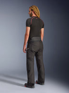 Alpinestars Andes V4 Drystar® Broek - Lang, adventure motorbroek, zwart, driekwart achteraanzicht op model, duurzaam textielontwerp met verstevigde panelen op het zitvlak en de knieën, voorzien van Alpinestars sterlogo, gedragen met zwarte basislaag en motorlaarzen