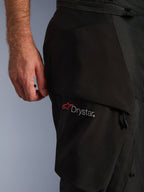Alpinestars Andes V4 Drystar® broek, close-up van het dijbeengedeelte, zwart textiel, voorzien van het witte Drystar-logo met een rode Alpinestars-ster, focus op het duurzame materiaal en de functionele zakconstructie