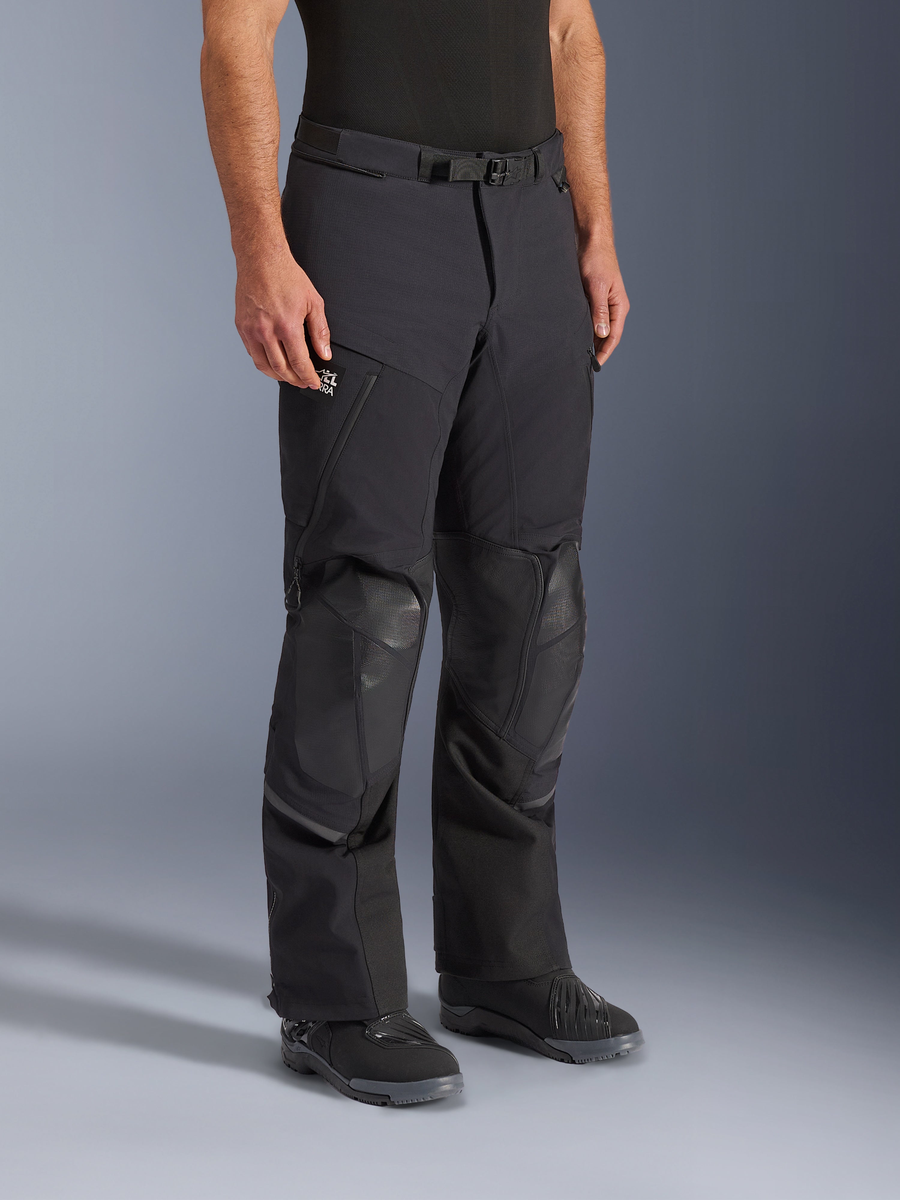 Alpinestars Andes Pro Drystar® XF Pants, zwart en donkergrijze adventure touring motorbroek, met versterkte kniebeschermingszones, zakken met rits en verstelbare tailleriem, getoond op een model met zwarte motorlaarzen