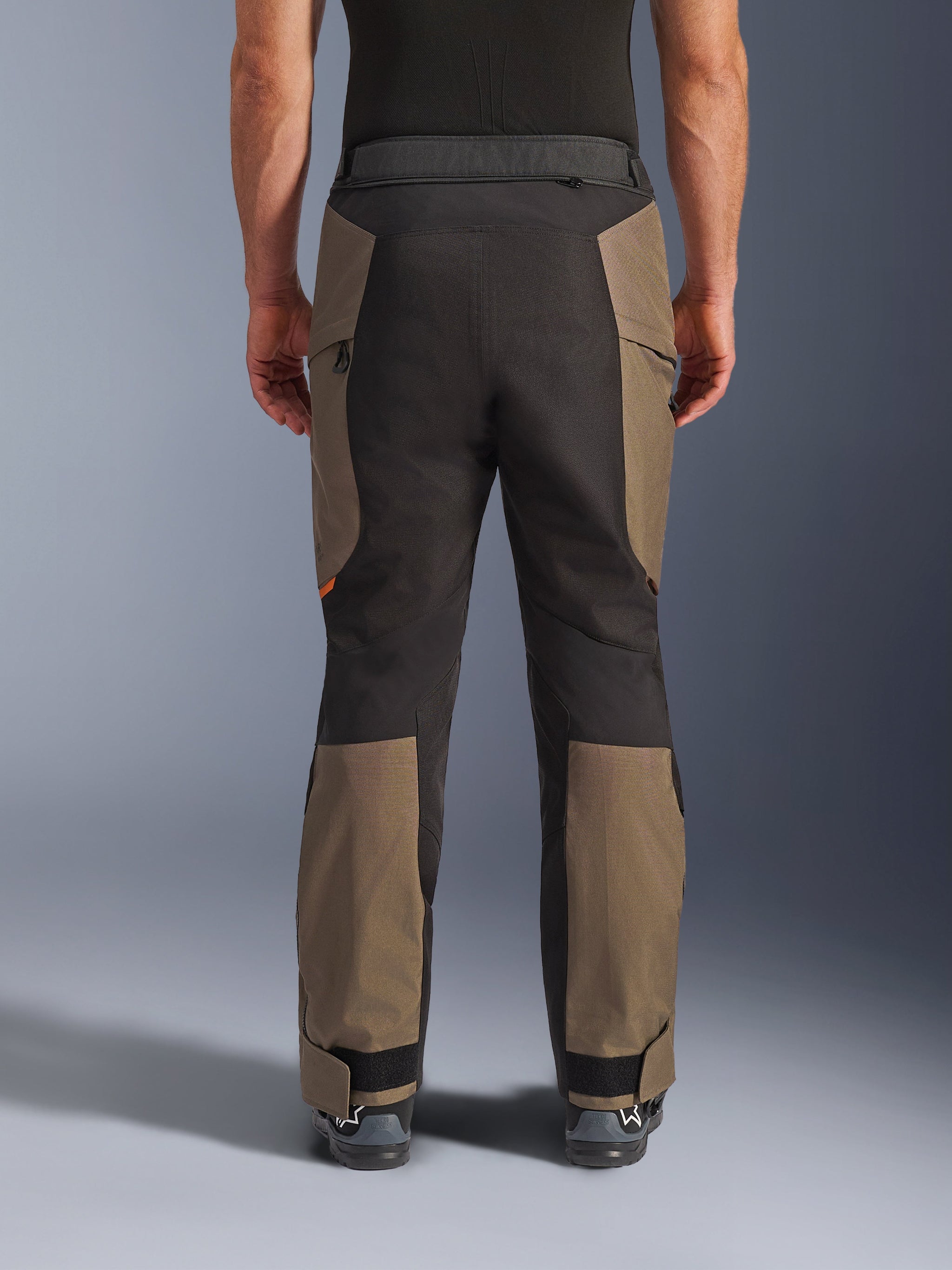 Alpinestars Cusco Drystar® broek, adventure motorbroek, Walnut Black, achteraanzicht op model, duurzame textielconstructie met kleurgeblokte panelen, verstelbare zoom en detail met rits in de taille voor touring en adventure rijden