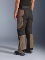 Alpinestars Cusco Drystar® broek, adventure motorbroek, Walnut Black met klein oranje accent, driekwart achteraanzicht toont de textielconstructie en walnut panelen, gedragen met zwarte motorlaarzen
