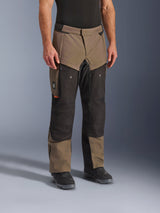 Alpinestars Cusco Drystar® broek, adventure motorbroek, Walnut Black, getoond op een model met zwarte laarzen, voorzien van een bruin en zwart multi-paneel ontwerp met ritszakken en versterkte knieën voor touring