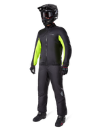 Alpinestars Bogota' Pro Drystar® 3 Seasons broek, zwart, motorrijder in volledige adventure touring uitrusting met een zwarte jas met neongele accenten, zwarte helm, handschoenen en laarzen, voorzien van het waterdichte Drystar® membraan gedragen over de broek