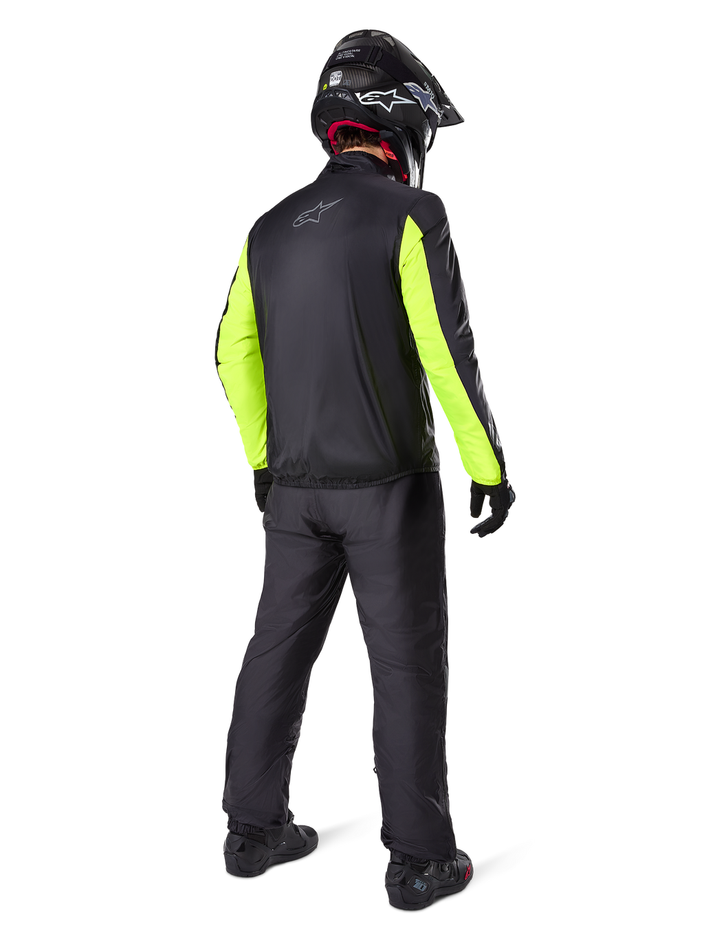 Alpinestars Bogotá Pro Drystar® 3 Seasons broek in het zwart, motorrijder van achteren gezien, zwart jack met fluorescerend gele mouwen, zwarte adventure helm en laarzen, complete adventure touring uitrusting