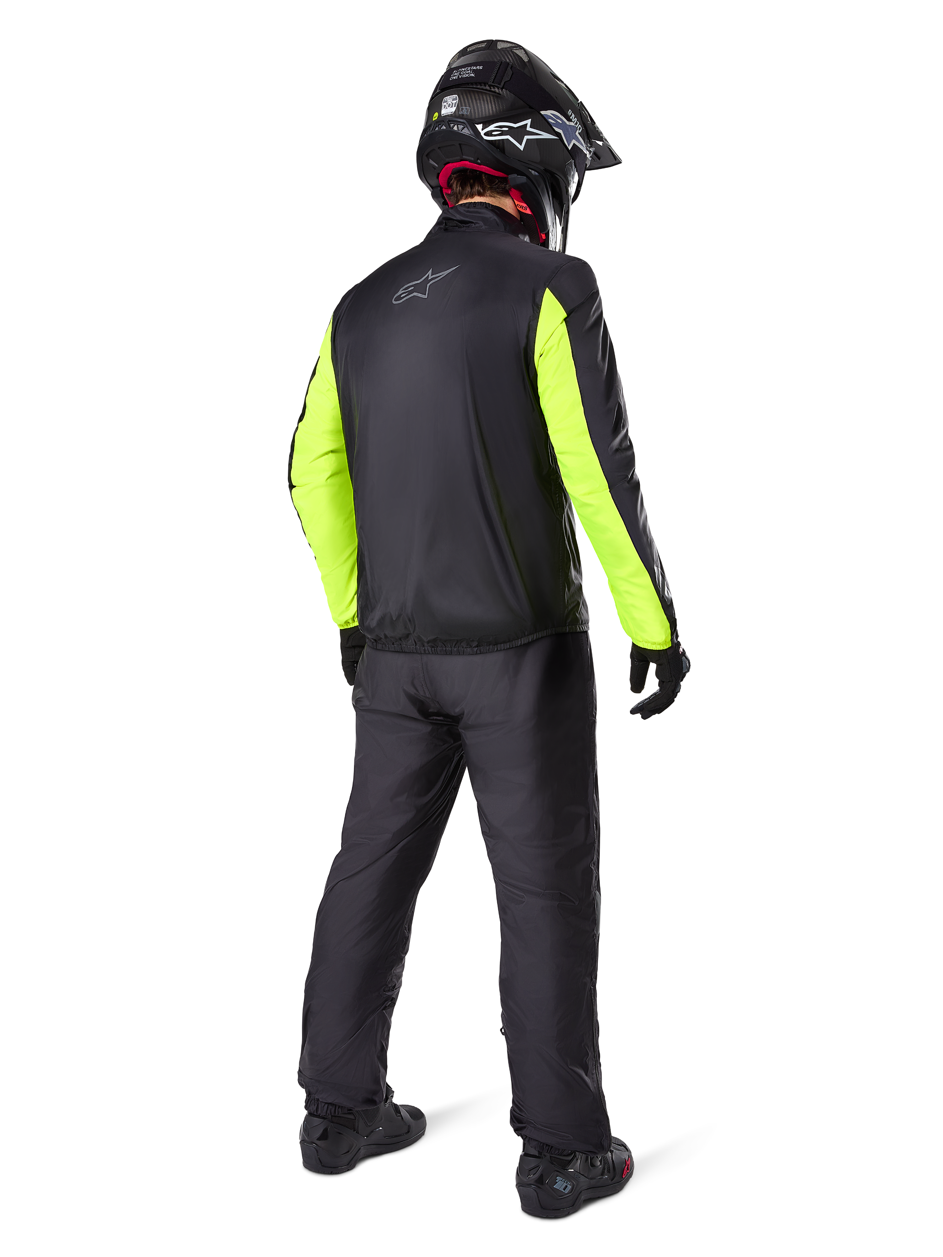 Alpinestars Bogotá Pro Drystar® 3 Seasons broek in het zwart, motorrijder van achteren gezien, zwart jack met fluorescerend gele mouwen, zwarte adventure helm en laarzen, complete adventure touring uitrusting