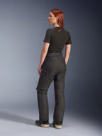 Alpinestars Stella Andes V4 Drystar® broek, zwarte adventure motorbroek, afgebeeld vanuit een zij-achteraanzicht op een model, gecombineerd met een zwart T-shirt en laarzen, voorzien van cargozakken met witte logo's en een duurzame textielconstructie.