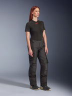 Alpinestars Stella Andes V4 Drystar® broek, motorbroek voor dames, zwart, gedragen met een zwart T-shirt met korte mouwen en rood logo en technische schoenen, adventure touring-ontwerp met versterkte panelen en ventilatieritsen, volledige lengte driekwart aanzicht