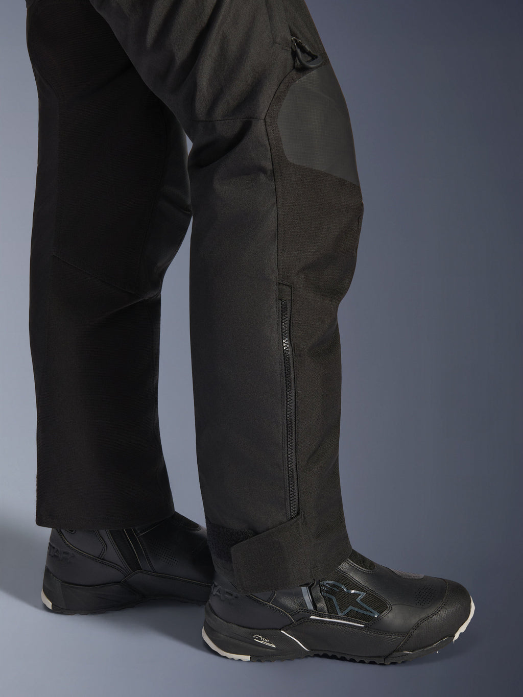 Alpinestars Stella Andes V4 Drystar® broek, motorbroek voor dames, zwart, close-up van het onderbeen met zijrits en verstelbare enkelmanchet, gedragen met zwarte Alpinestars motorlaarzen