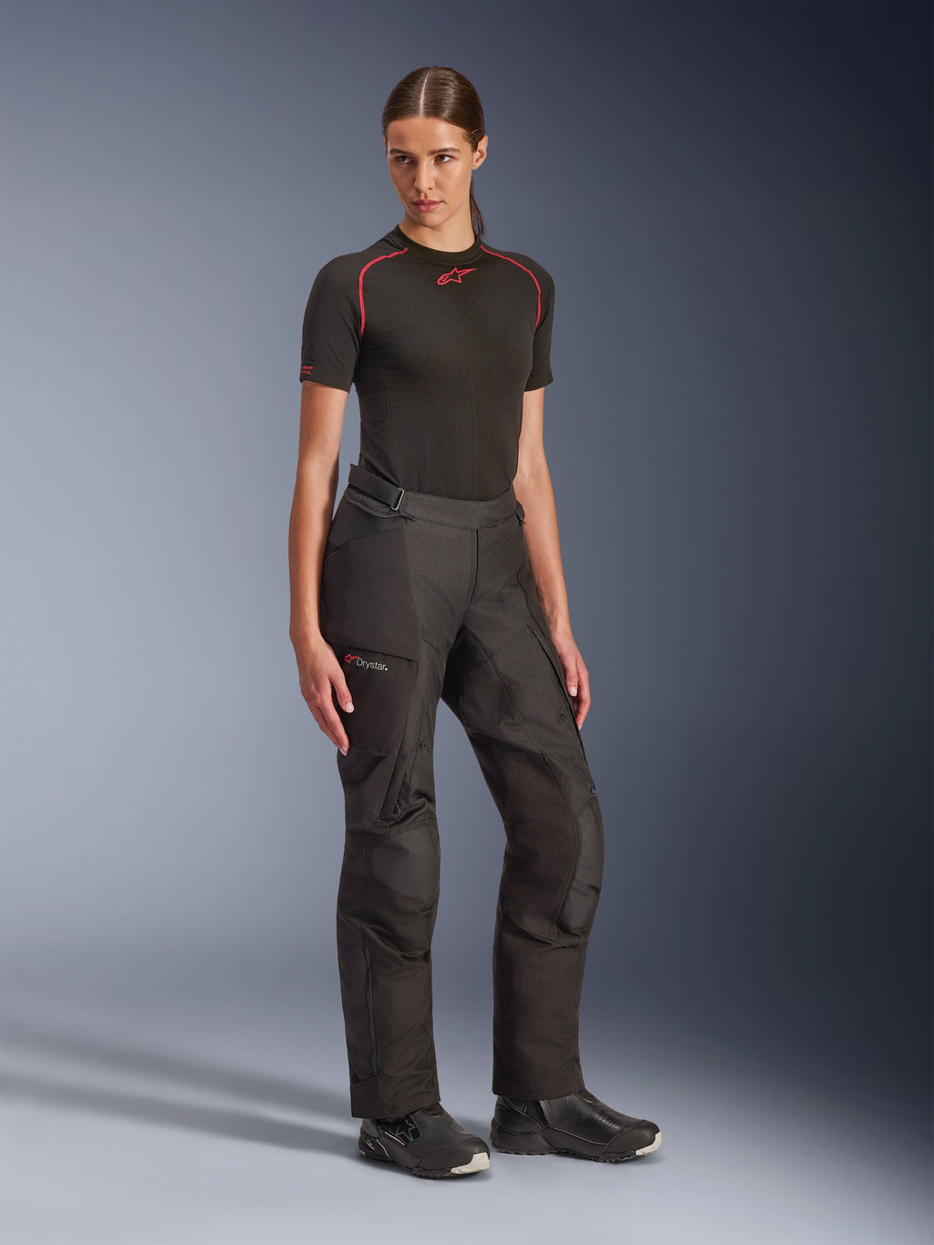 Alpinestars Stella Andes V4 Drystar® broek, zwart, adventure touring motorbroek voor dames, gedragen met een zwarte basislaag met korte mouwen en zwarte motorlaarzen, voorzien van waterdichte Drystar®-technologie en cargo-zakken