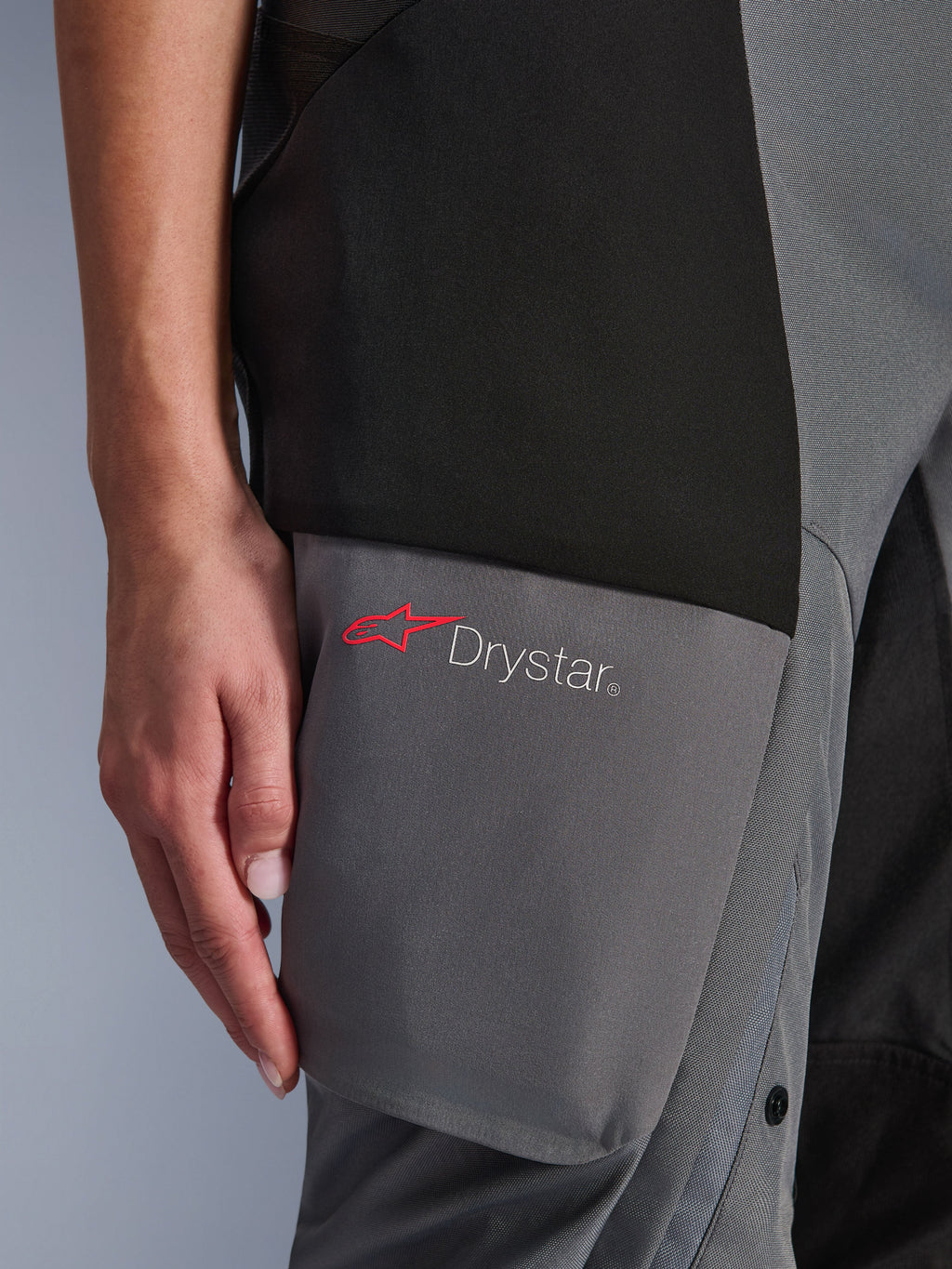 Alpinestars Stella Andes V4 Drystar® broek, adventure-touring damesbroek, zwart en donkergrijs, detail van de dij met het Drystar-logo en de rode Alpinestars-ster op verstevigde textielpanelen