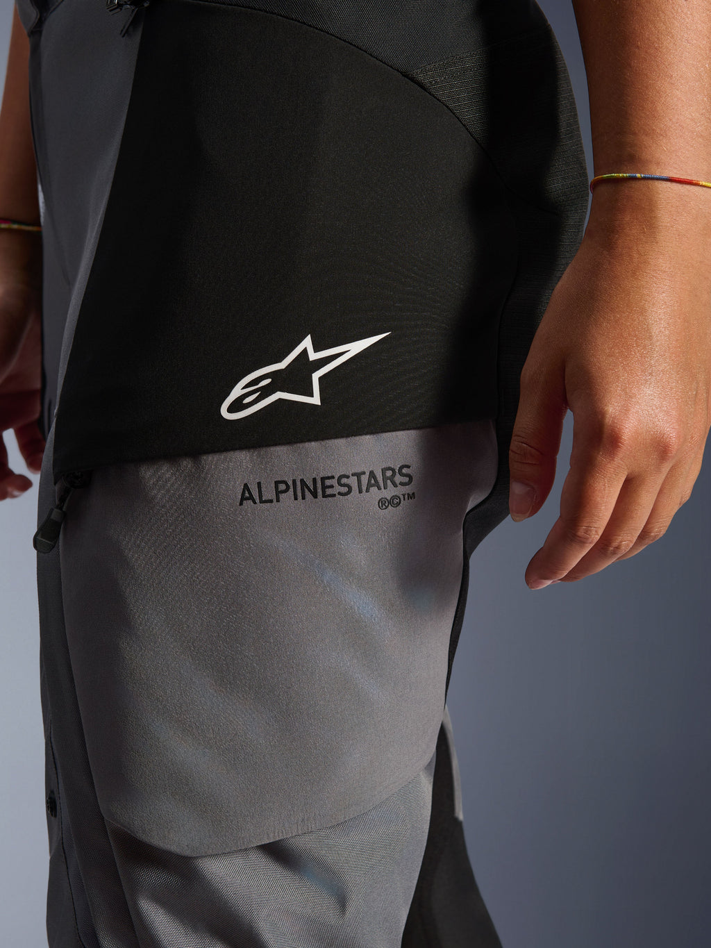 Stella Andes V4 Drystar® damesbroek, zwart en donkergrijs, close-up van het bovenbeen met wit sterlogo en zwarte Alpinestars-branding, duurzaam adventure touring textielmateriaal