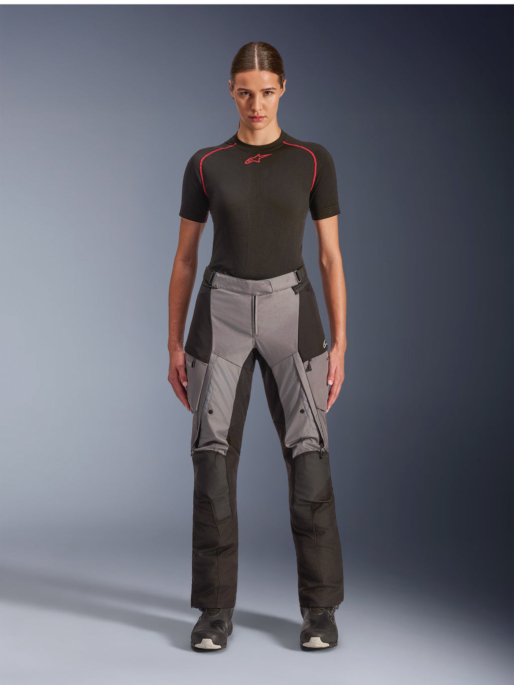 Alpinestars Stella Andes V4 Drystar broek, adventure touring motorbroek voor dames, zwart en donkergrijs, gedragen door een vrouwelijk model met een zwarte basislaag en motorlaarzen, voorzien van versterkte textielpanelen en cargozakken voor adventure ritten