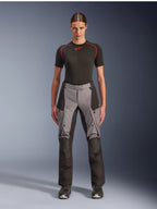 Alpinestars Stella Andes V4 Drystar broek, adventure touring motorbroek voor dames, zwart en donkergrijs, gedragen door een vrouwelijk model met een zwarte basislaag en motorlaarzen, voorzien van versterkte textielpanelen en cargozakken voor adventure ritten