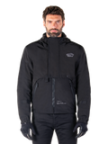 Alpinestars Mootant Waterproof Parka, zwarte motorjas met capuchon en een modulair technisch ontwerp, gedragen door een mannelijk model met zwarte handschoenen, voorzien van een unieke borstflap en zijzakken met rits, urban en touring rijstijl