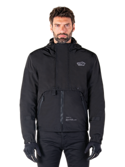 Alpinestars Mootant Waterproof Parka, Black hooded motorcycle jacket with a modular technical design, worn by a male model with black gloves, featuring a unique chest flap and zippered side pockets, urban and touring riding style.