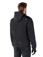 Alpinestars Mootant Waterproof Parka, zwarte motorjas, achteraanzicht met capuchon, wit logo op de schouder en reflecterende MO.ST.EQ.-branding op de onderrug, urban contemporary motorkleding