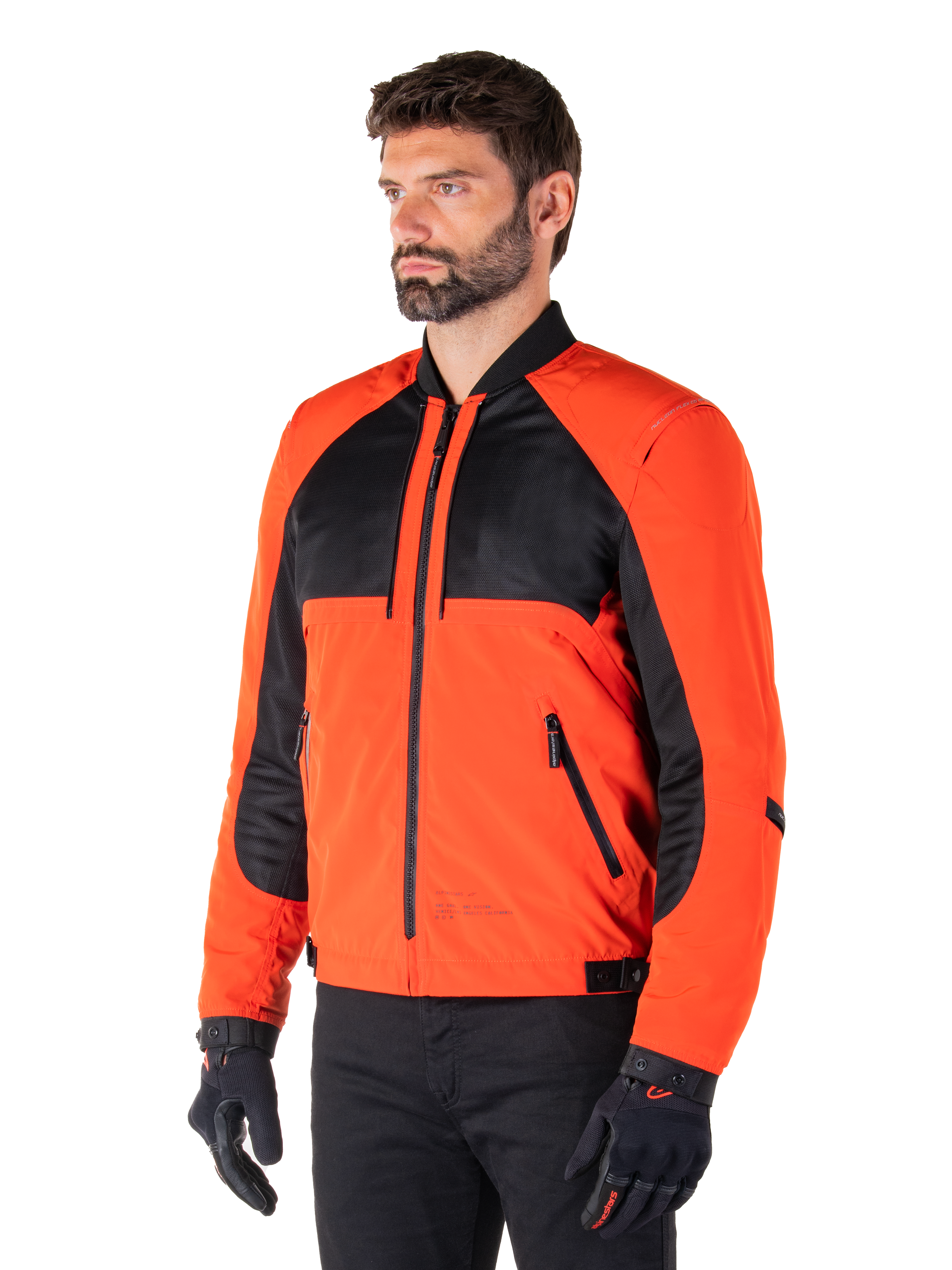 Alpinestars Mootant Waterproof Parka in Spicy Orange en zwart, modulaire motorjas getoond in bomber-configuratie, voorzien van zwart mesh en oranje textielpanelen, urban contemporary motorkleding gedragen met zwarte handschoenen