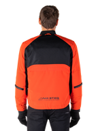 Alpinestars Mootant Waterproof Parka, motorjas, Spicy Orange en zwart, achteraanzicht, met zwart mesh op de bovenrug en een oranje onderpaneel met MO.ST.EQ.-logo, gedragen met een zwarte broek en handschoenen.