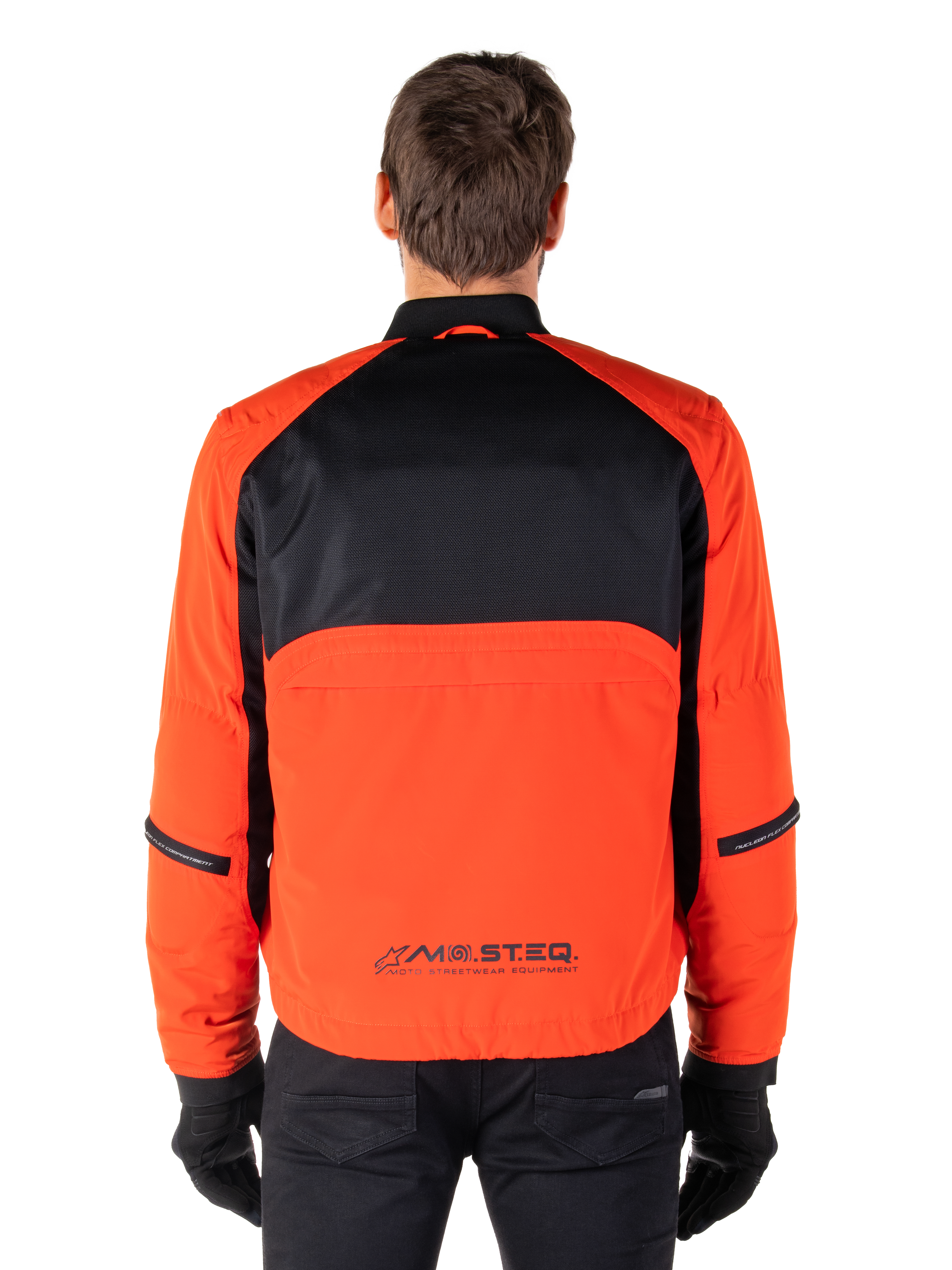 Alpinestars Mootant Waterproof Parka, motorjas, Spicy Orange en zwart, achteraanzicht, met zwart mesh op de bovenrug en een oranje onderpaneel met MO.ST.EQ.-logo, gedragen met een zwarte broek en handschoenen.
