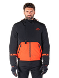 Alpinestars Mootant Waterproof Parka, modulaire motorjas in Spicy Orange en zwart, gedragen door een model met bijpassende handschoenen, voorzien van een ontwerp met capuchon en tweekleurige panelen, ritssluiting aan de voorzijde en verstelbare manchetten, urban contemporary motorkleding