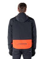 Alpinestars Mootant Waterproof Parka in Spicy Orange en zwart, achteraanzicht met zwart bovendeel met capuchon en oranje onderpaneel voorzien van het MO.ST.EQ. woordmerk, functionele motor-streetwear.