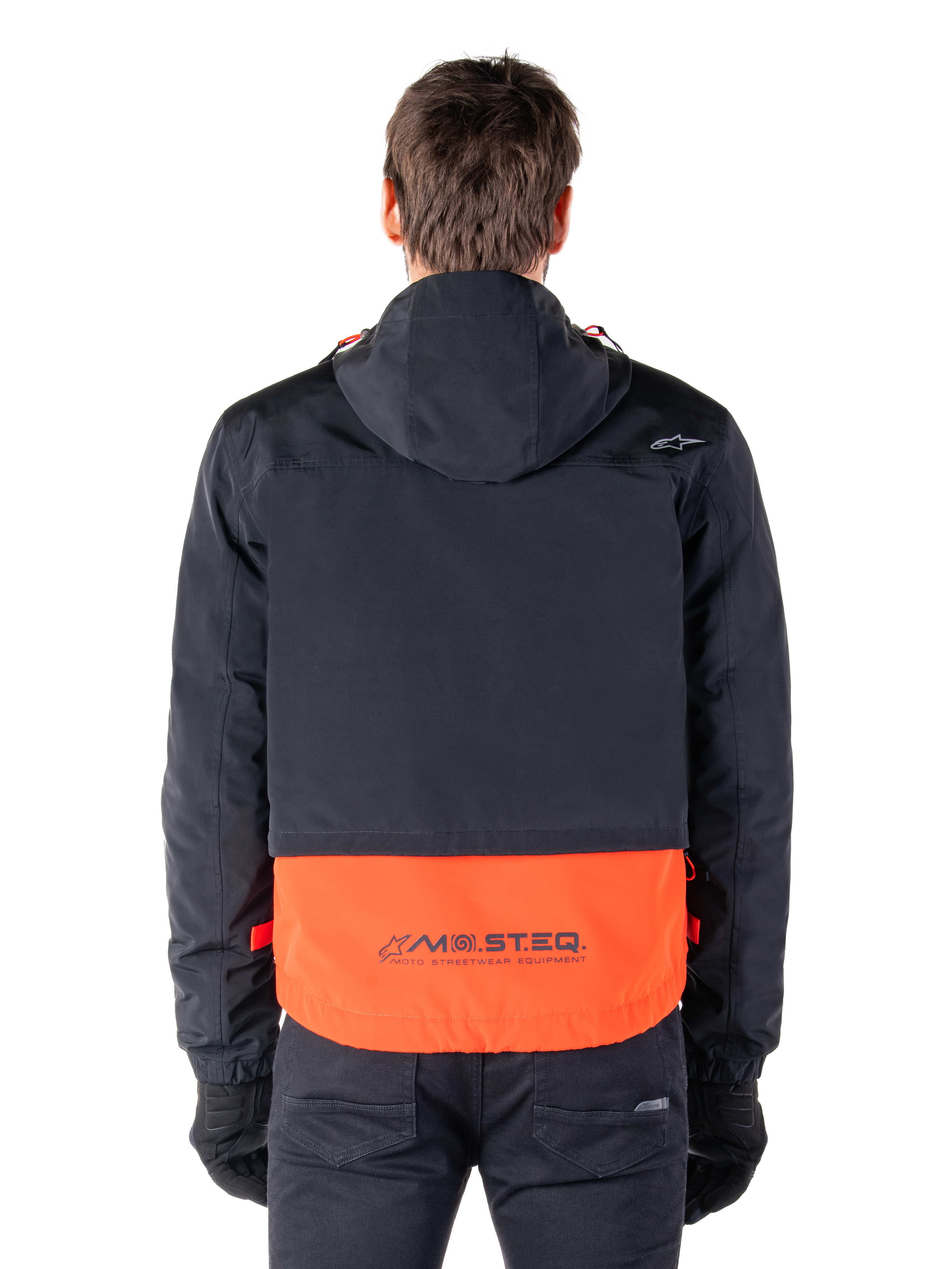 Alpinestars Mootant Waterproof Parka in Spicy Orange en zwart, achteraanzicht met zwart bovendeel met capuchon en oranje onderpaneel voorzien van het MO.ST.EQ. woordmerk, functionele motor-streetwear.