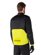 Alpinestars Mootant Waterproof Parka, motorjas, Lime Punch en zwart, achteraanzicht met zwarte mesh bovenzijde en fel limoengroen onderste deel, voorzien van MO.ST.EQ.-branding, gedragen met zwarte motorbroek en handschoenen